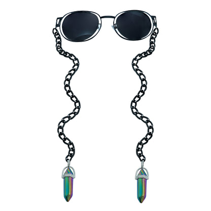 A pair of round, dark-lensed sunglasses with a silver frame is connected to a black chain, which holds a pendant shaped holographic vibrant rainbow crystal-front view